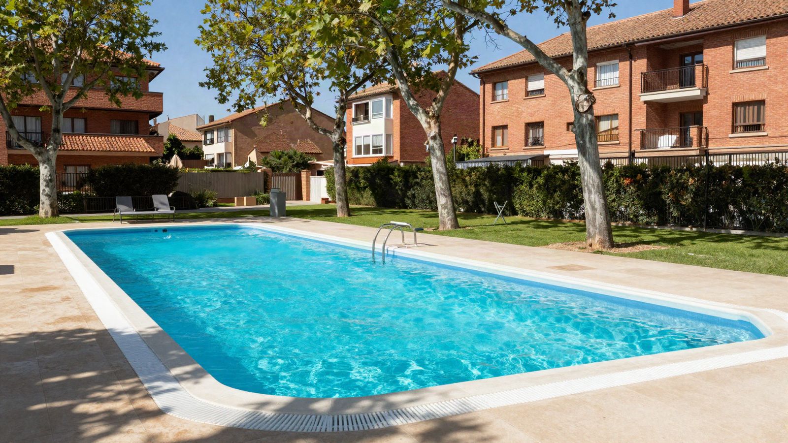 Community pool among brick apartment buildings and shade trees
