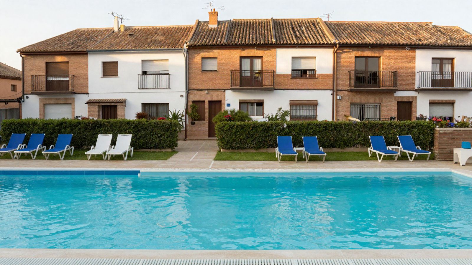 Piscina comunitaria de una hilera de chalets adosados con tumbonas